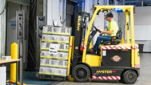 A forklift loading a pallet via a warehouse dock door. Cameras either side of the door use Viziotix barcode scanner software to scan the pallet label.